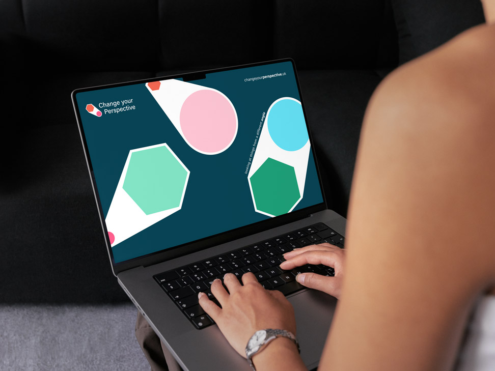 Person using a laptop displaying a Change Your Perspective branded virtual meeting background with geometric shapes in pink, green, and blue, and the company logo in the top left corner.